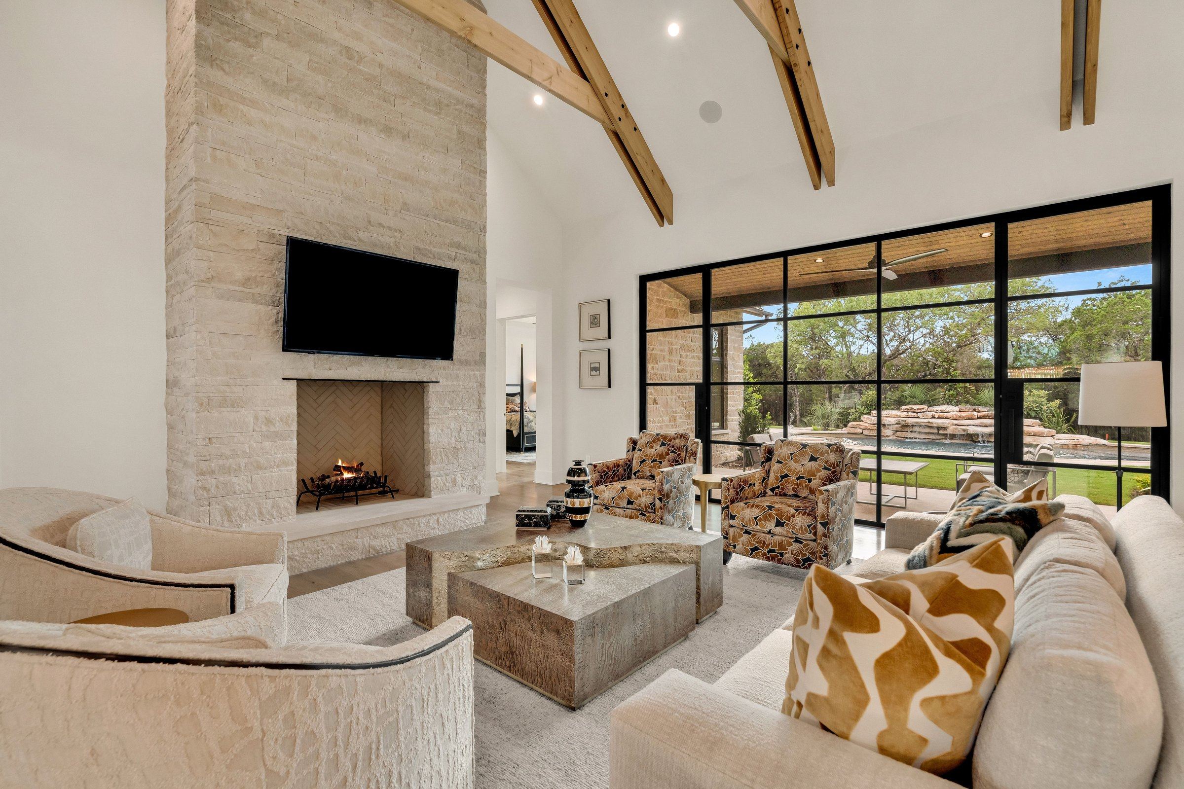 Great room with cut stone fireplace, vaulted ceiling, and pool views at 4300 Amarra Drive
